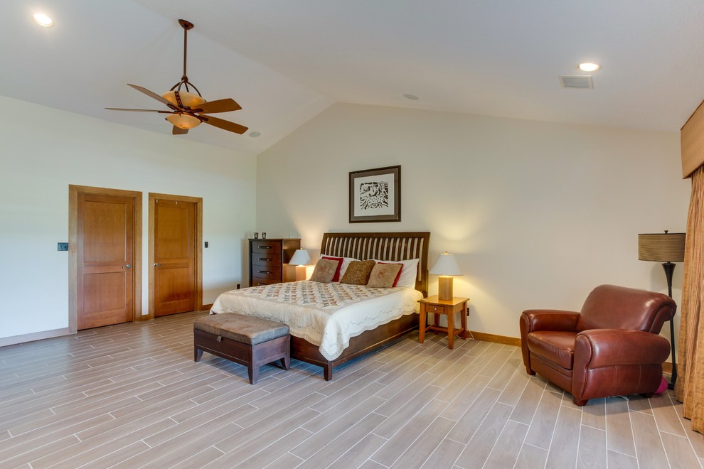 Großes Klassisches Hauptschlafzimmer ohne Kamin mit Porzellan-Bodenfliesen, beiger Wandfarbe und beigem Boden in Houston