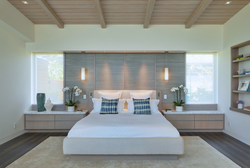 Mittelgroßes Hauptschlafzimmer mit beiger Wandfarbe, dunklem Holzboden, braunem Boden und freigelegten Dachbalken in Hawaii
