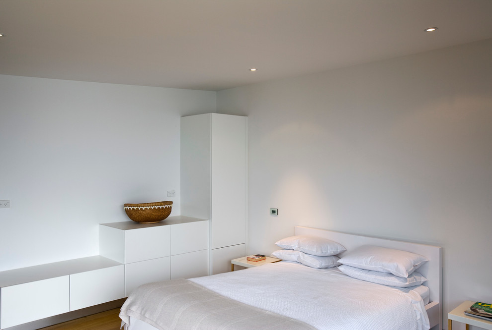 Diseño de habitación de invitados moderna sin chimenea con paredes blancas