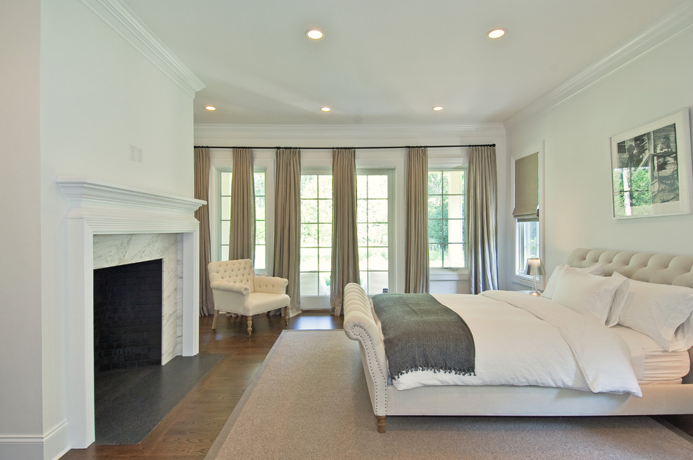 Imagen de dormitorio clásico con paredes blancas, suelo de madera oscura y todas las chimeneas