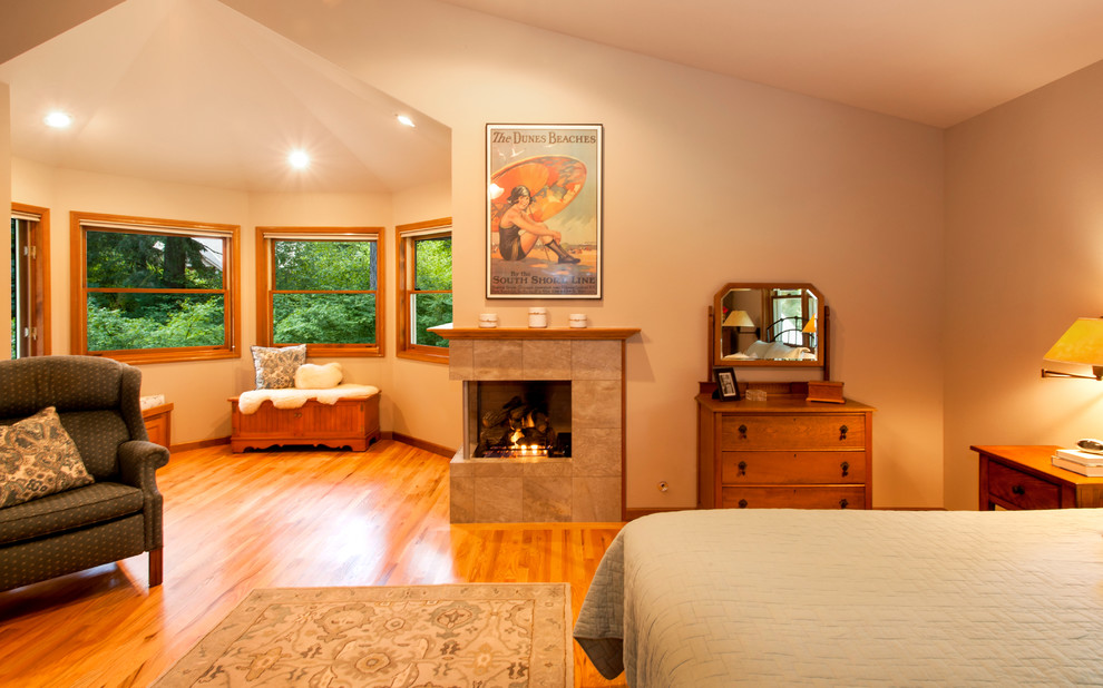 Ejemplo de dormitorio principal minimalista grande con paredes blancas, suelo de madera en tonos medios, chimenea de esquina y marco de chimenea de baldosas y/o azulejos