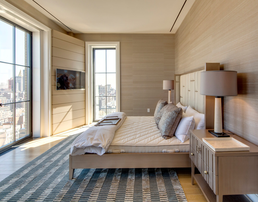 This is an example of a traditional bedroom in New York with beige walls and light hardwood flooring.