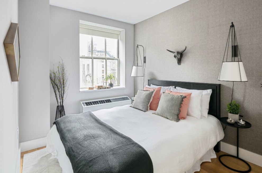 Exemple d'une petite chambre d'amis moderne avec un mur gris, parquet clair et aucune cheminée.