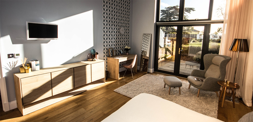 Foto de dormitorio principal actual grande con paredes grises y suelo de madera en tonos medios