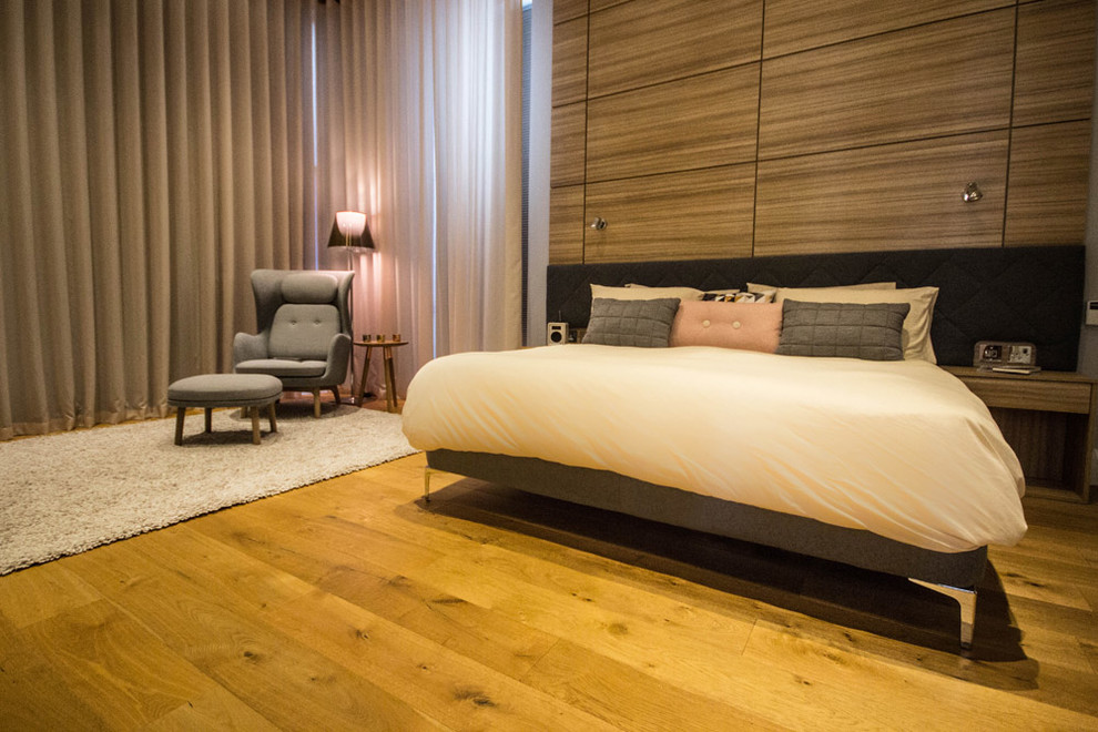 Imagen de dormitorio principal actual grande con paredes grises y suelo de madera en tonos medios