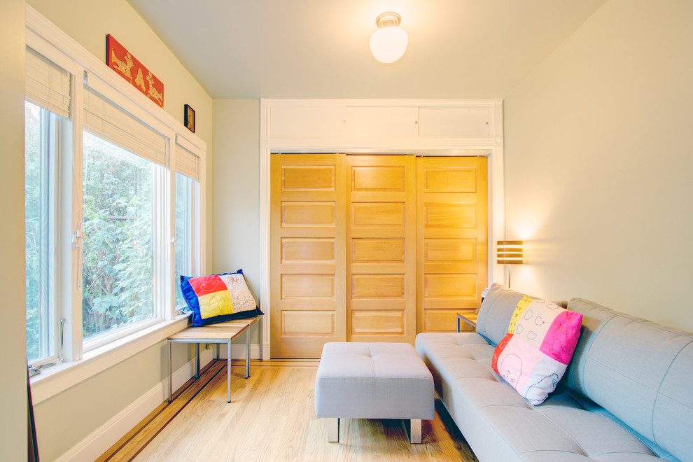 Ejemplo de habitación de invitados ecléctica de tamaño medio sin chimenea con paredes beige y suelo de madera clara