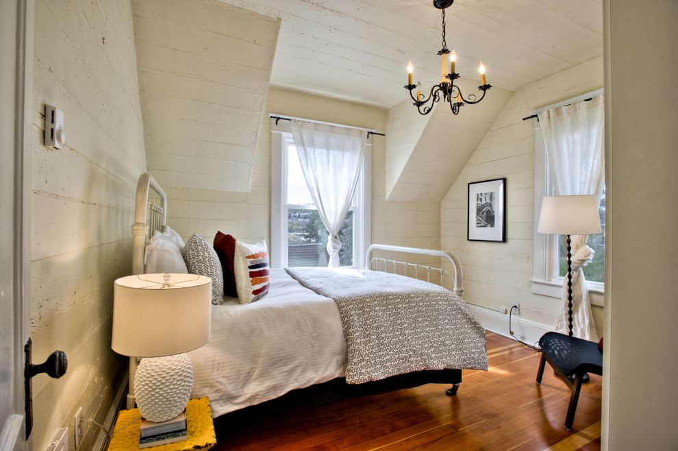 Farmhouse bedroom in Seattle with white walls and dark hardwood flooring.