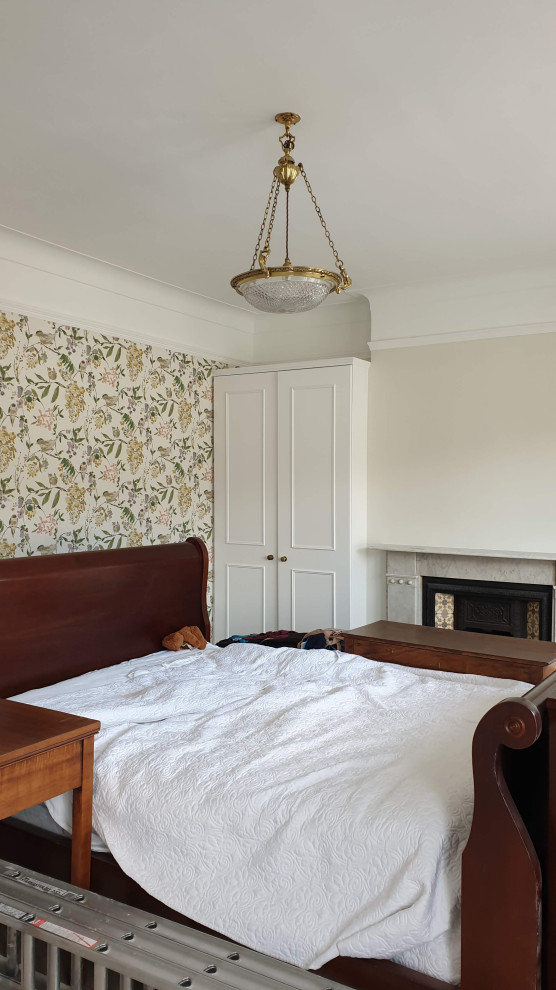 Photo of a large traditional master bedroom in London with green walls, carpet, a standard fireplace, a stone fireplace surround, green floors, a drop ceiling and wallpapered walls.