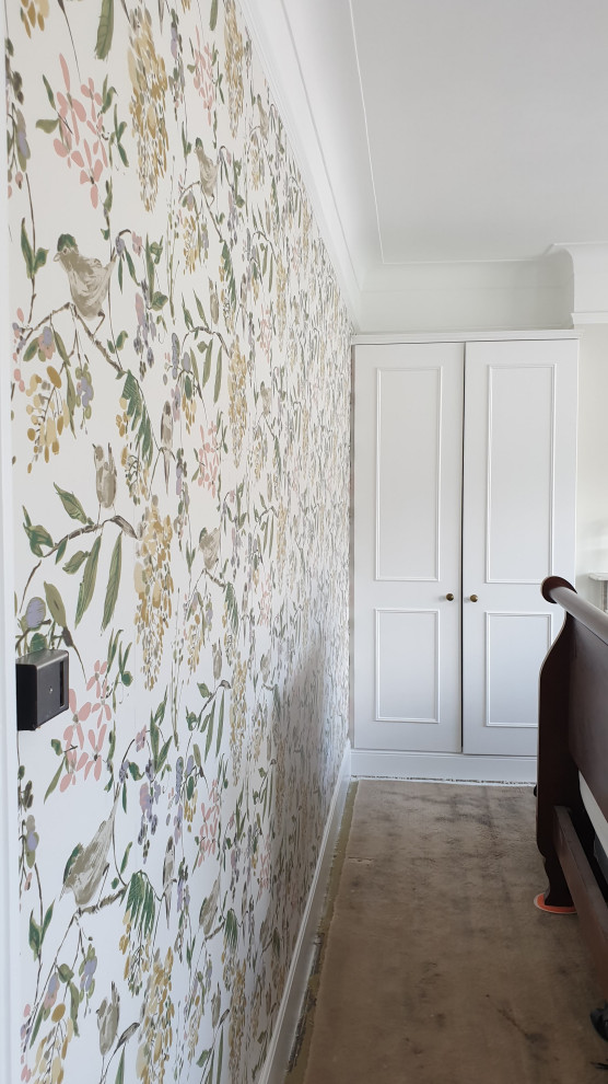 Photo of a large traditional master bedroom in London with green walls, carpet, a standard fireplace, a stone fireplace surround, green floors, a drop ceiling and wallpapered walls.