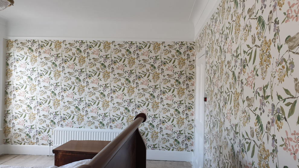 Großes Klassisches Hauptschlafzimmer mit grüner Wandfarbe, Teppichboden, Kamin, Kaminumrandung aus Stein, grünem Boden, eingelassener Decke und Tapetenwänden in London