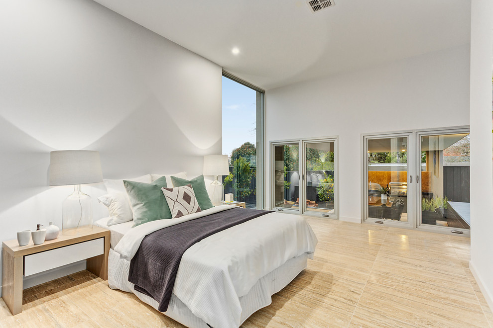 This is an example of a large contemporary master bedroom in Melbourne with white walls, travertine flooring and no fireplace.