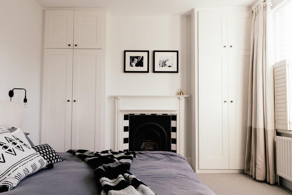 ロンドンにある中くらいなコンテンポラリースタイルのおしゃれな客用寝室 (白い壁、カーペット敷き、標準型暖炉、タイルの暖炉まわり)