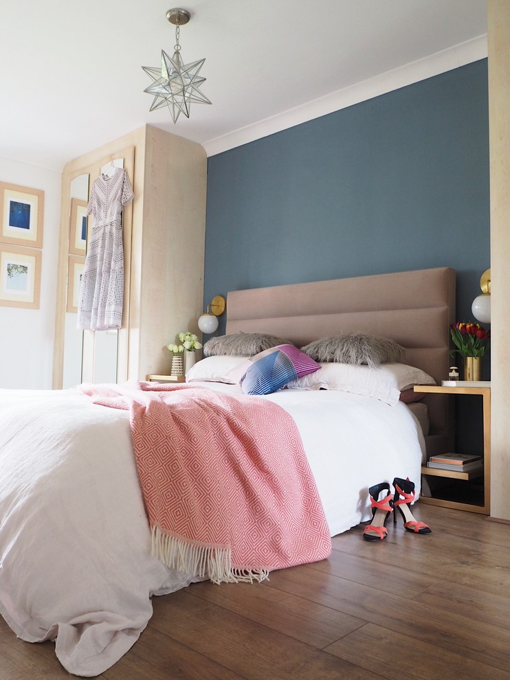 Diseño de dormitorio principal bohemio de tamaño medio con paredes azules, suelo laminado y suelo marrón