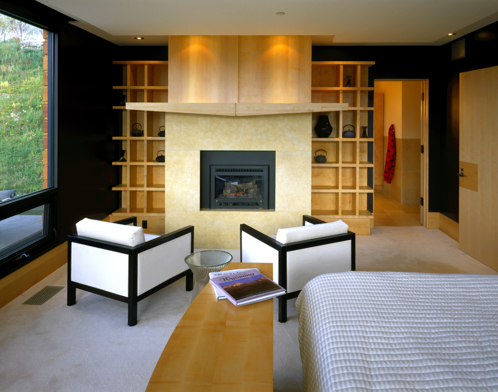 На фото: хозяйская спальня среднего размера в стиле модернизм с черными стенами, ковровым покрытием, стандартным камином и фасадом камина из дерева