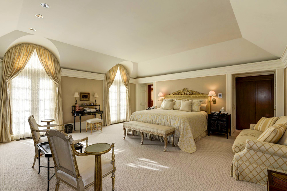 Imagen de dormitorio principal grande sin chimenea con paredes beige, moqueta, suelo marrón y bandeja