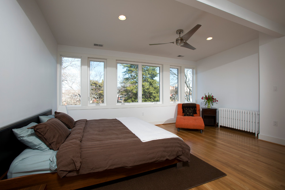 На фото: большая хозяйская спальня в современном стиле с белыми стенами и светлым паркетным полом без камина