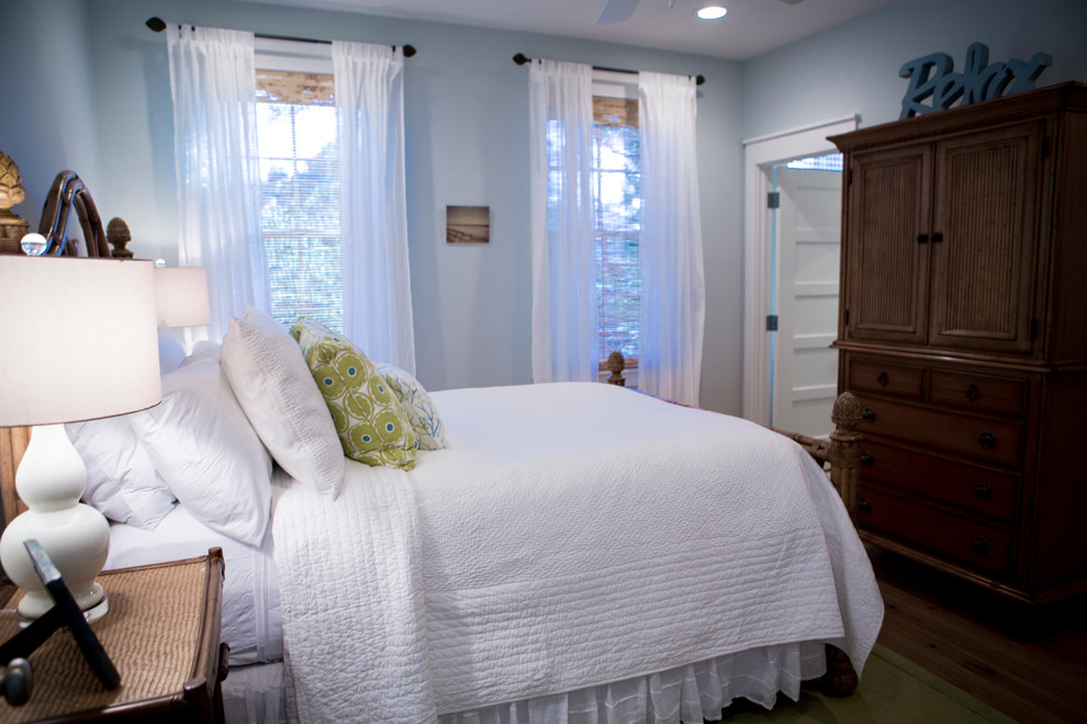 Modelo de dormitorio principal costero de tamaño medio sin chimenea con paredes azules y suelo de madera en tonos medios