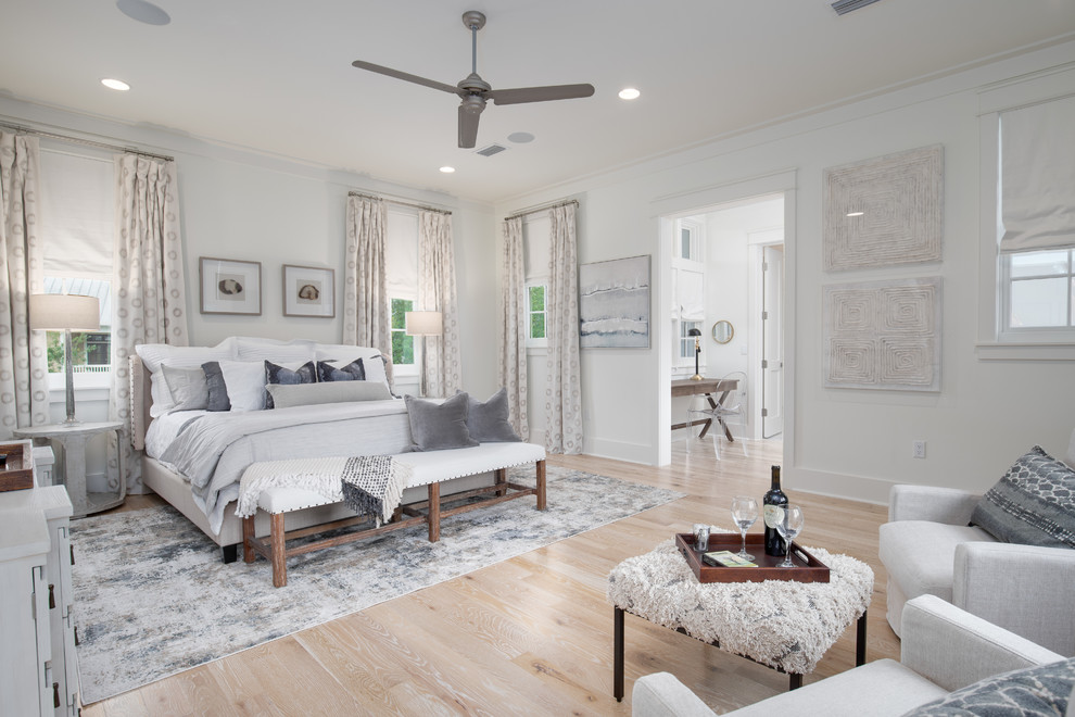 This is an example of a coastal bedroom in Miami with white walls, light hardwood flooring, no fireplace and beige floors.