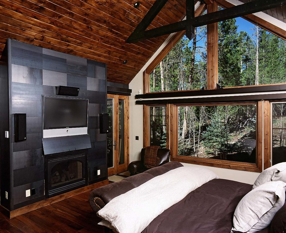 На фото: большая хозяйская спальня в современном стиле с стандартным камином и фасадом камина из дерева