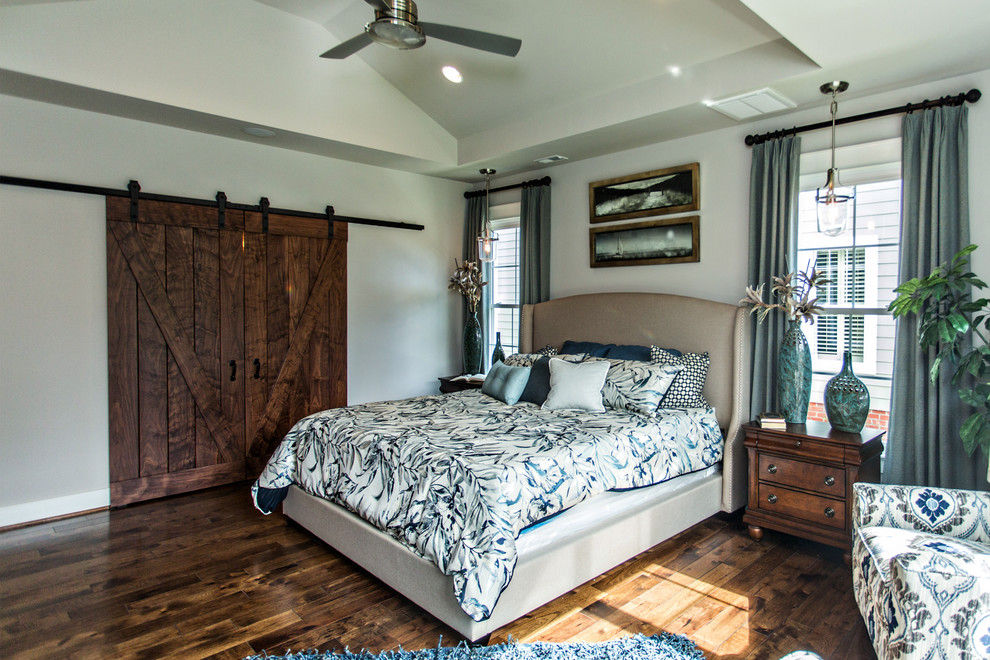 Modelo de dormitorio principal campestre de tamaño medio con paredes grises, suelo de madera oscura y suelo marrón