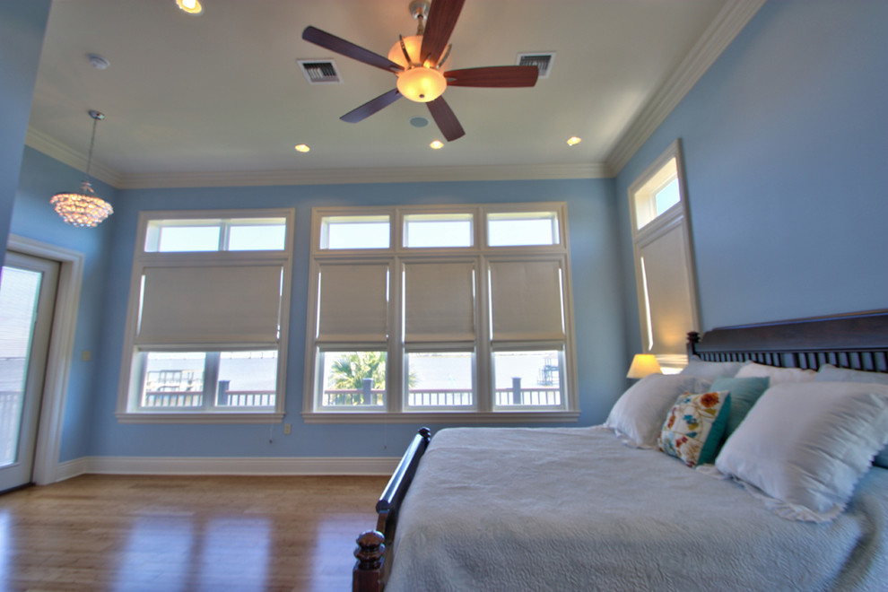Diseño de dormitorio principal marinero de tamaño medio sin chimenea con paredes azules y suelo de madera en tonos medios