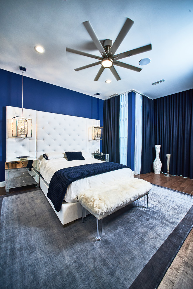 Imagen de dormitorio principal actual extra grande sin chimenea con paredes azules, suelo de madera en tonos medios y suelo marrón