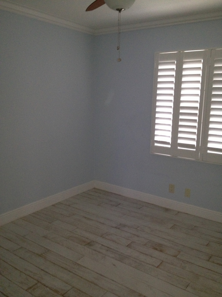 Ejemplo de habitación de invitados costera pequeña con paredes azules, suelo laminado y suelo blanco
