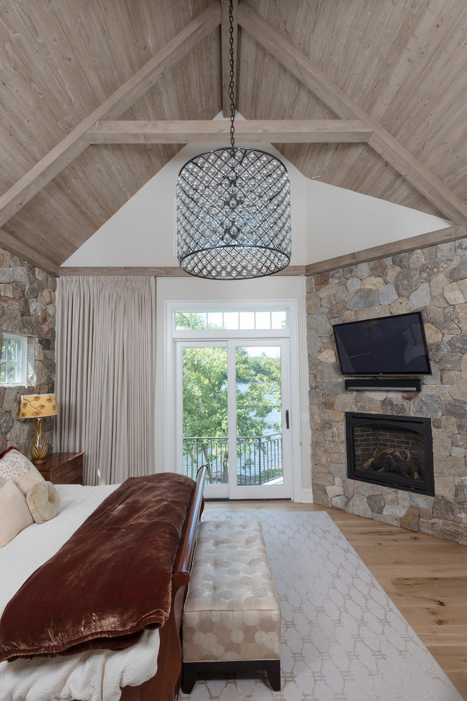 Foto de dormitorio principal tradicional renovado grande con paredes blancas, suelo de madera clara, todas las chimeneas, marco de chimenea de metal y suelo marrón