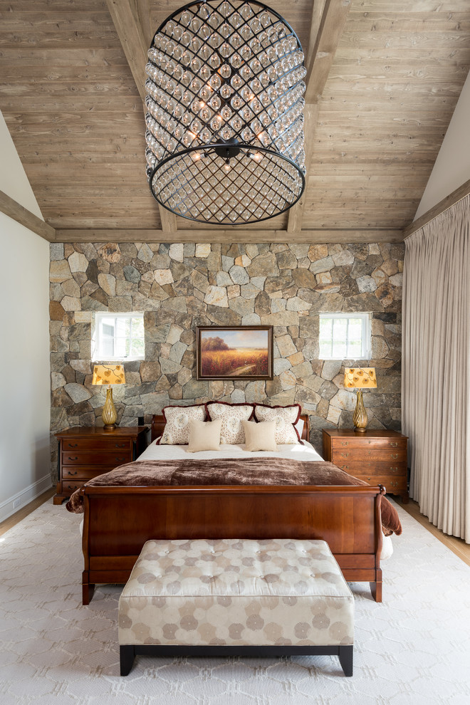 Foto de dormitorio principal de estilo de casa de campo grande con paredes blancas, suelo de madera clara, todas las chimeneas, marco de chimenea de metal y suelo marrón