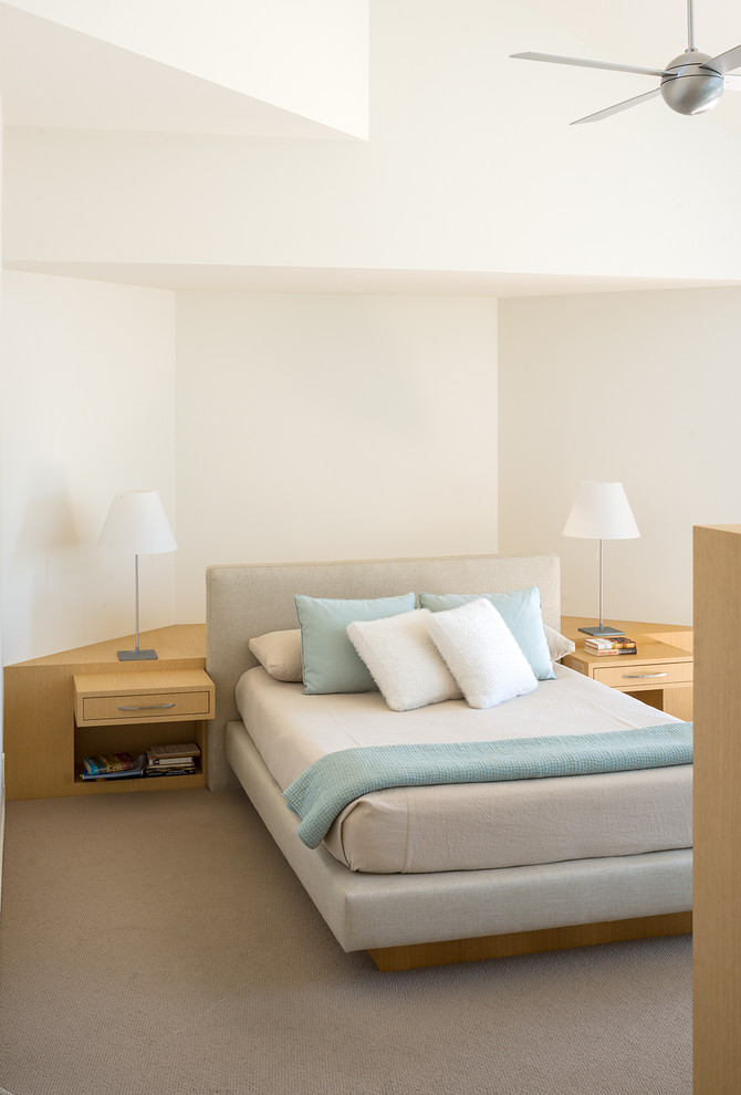 Modern inredning av ett sovrum, med vita väggar och heltäckningsmatta