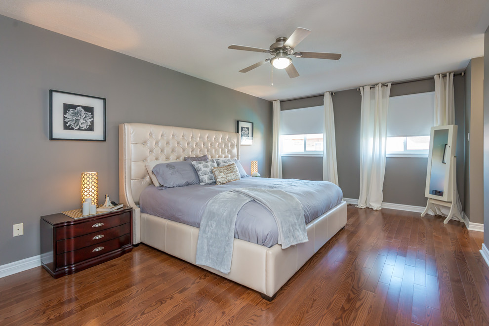 Ejemplo de dormitorio principal tradicional de tamaño medio con paredes grises, suelo de madera en tonos medios y suelo marrón