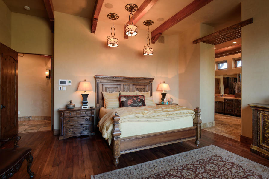 Aménagement d'une chambre parentale sud-ouest américain de taille moyenne avec un mur beige, parquet foncé, une cheminée standard et un manteau de cheminée en plâtre.