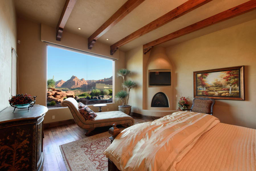 Exemple d'une chambre parentale sud-ouest américain de taille moyenne avec un mur beige, parquet foncé, une cheminée standard et un manteau de cheminée en plâtre.