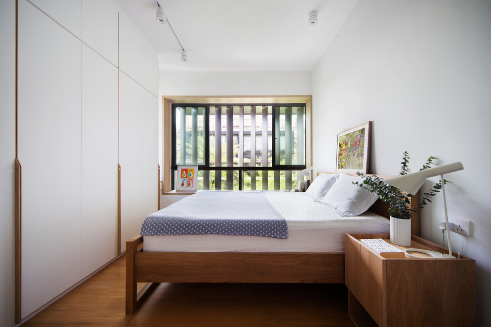 Diseño de dormitorio principal moderno con paredes blancas, suelo de madera en tonos medios y suelo marrón