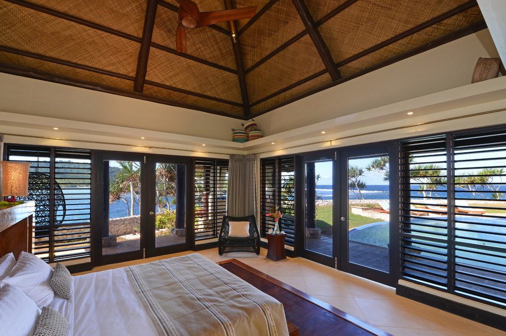 Imagen de dormitorio principal tropical de tamaño medio con paredes beige y suelo de baldosas de cerámica