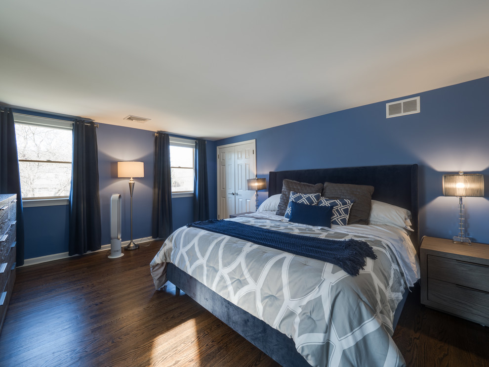 Modelo de dormitorio principal tradicional renovado grande con paredes azules, suelo de madera oscura y suelo marrón