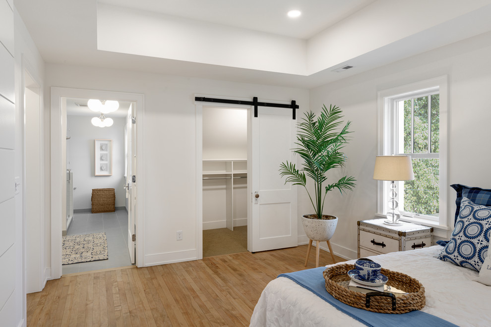 Ejemplo de dormitorio principal tradicional de tamaño medio con paredes blancas, suelo de madera clara y suelo marrón