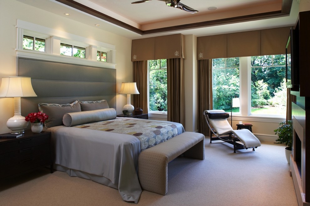 Cette image montre une grande chambre design avec un mur beige, une cheminée standard, un manteau de cheminée en pierre et un sol beige.
