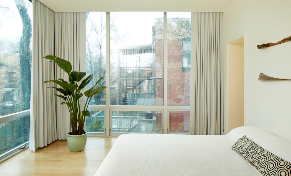 Foto de dormitorio principal contemporáneo de tamaño medio con paredes beige y suelo de madera clara