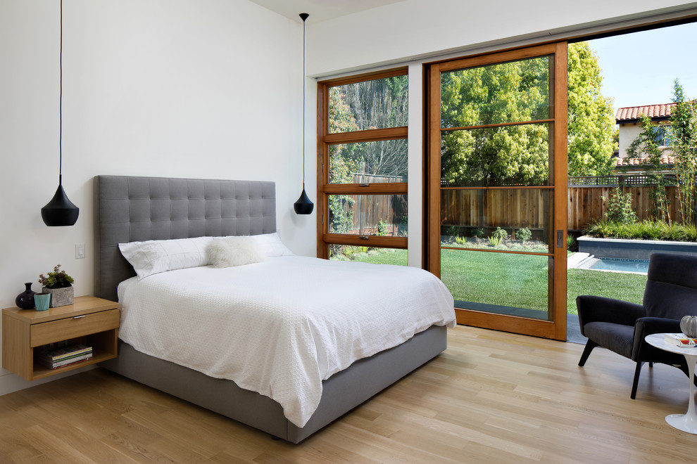 Ispirazione per una camera da letto minimal con pareti bianche, parquet chiaro e pavimento beige