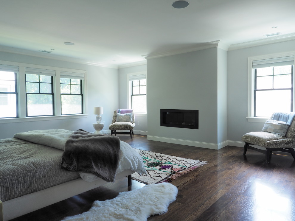 Imagen de dormitorio principal clásico de tamaño medio con paredes azules, suelo de madera en tonos medios, todas las chimeneas y marco de chimenea de yeso