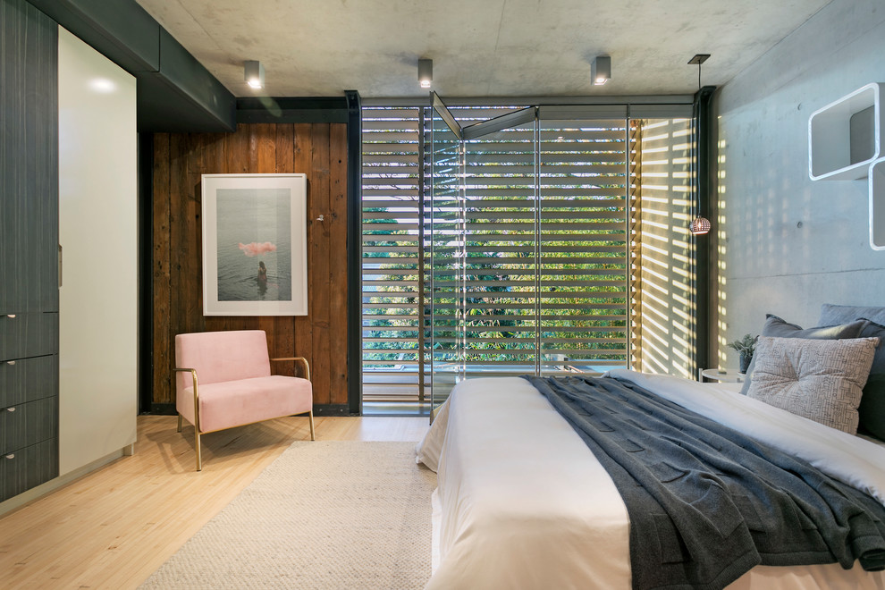 Immagine di una camera matrimoniale industriale con pareti grigie, pavimento in bambù e pavimento beige