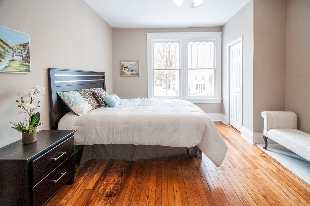 Imagen de dormitorio actual de tamaño medio con paredes marrones y suelo de madera en tonos medios