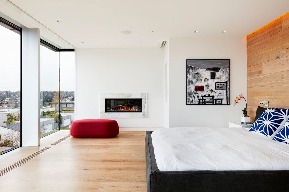 Inspiration for a large contemporary master light wood floor bedroom remodel in Vancouver with white walls, a standard fireplace and a stone fireplace