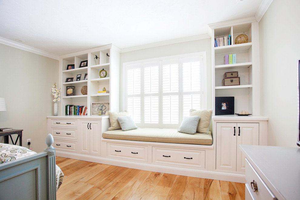 Modelo de dormitorio principal de tamaño medio sin chimenea con paredes beige y suelo de madera clara