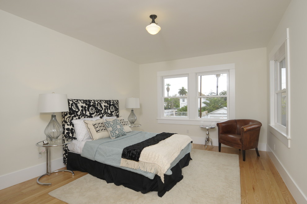 This is an example of a large traditional master bedroom in Los Angeles with white walls and light hardwood flooring.