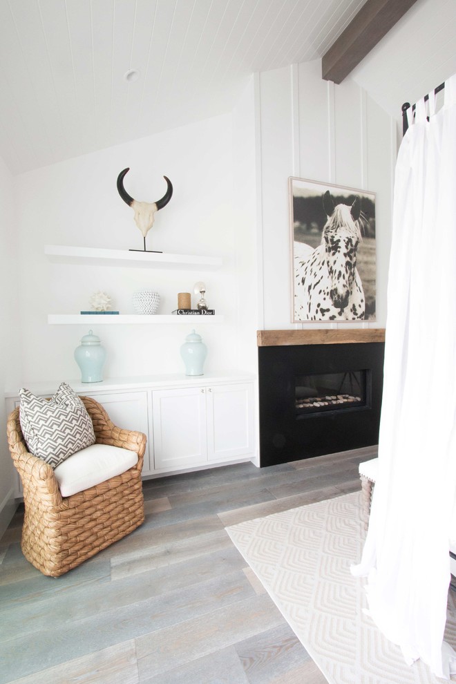 Maritimes Hauptschlafzimmer mit weißer Wandfarbe, dunklem Holzboden, Gaskamin und Kaminumrandung aus Stein in Orange County