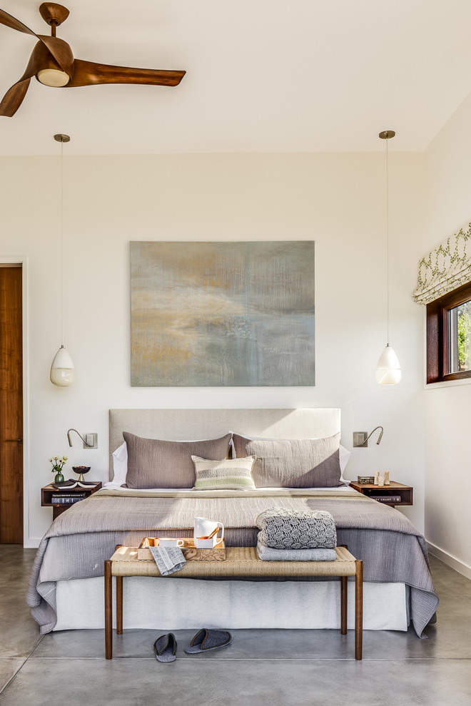 World-inspired master and grey and brown bedroom in San Francisco with white walls, concrete flooring and grey floors.
