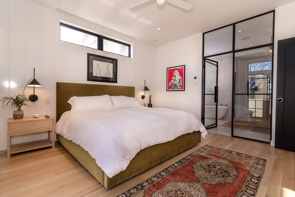 Ejemplo de dormitorio principal actual de tamaño medio con paredes blancas, suelo de madera clara y suelo beige
