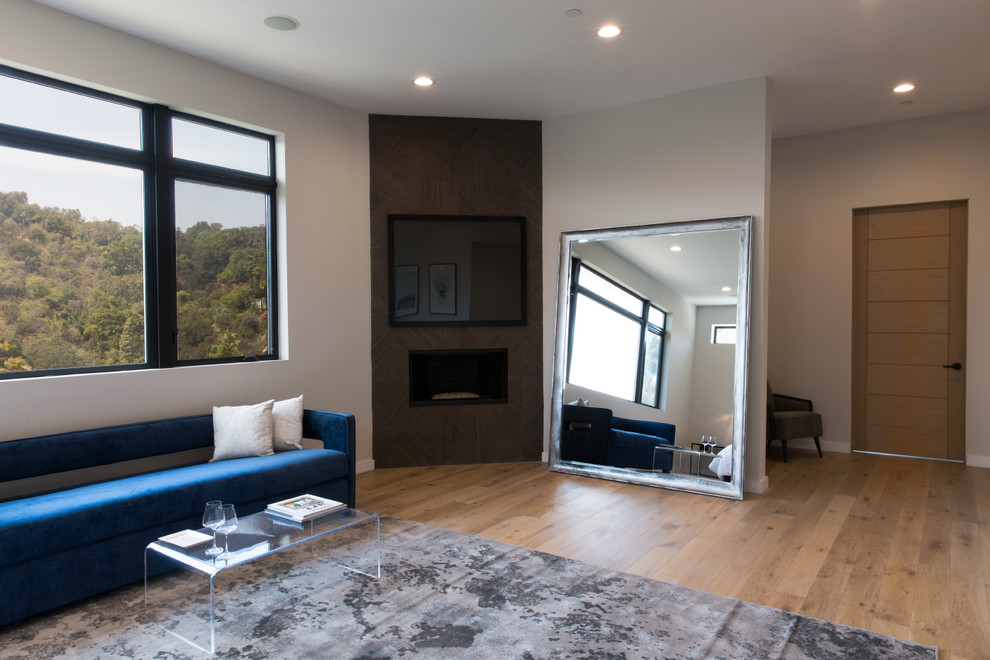 Example of a mid-sized minimalist master light wood floor bedroom design in Los Angeles with white walls, a ribbon fireplace and a tile fireplace